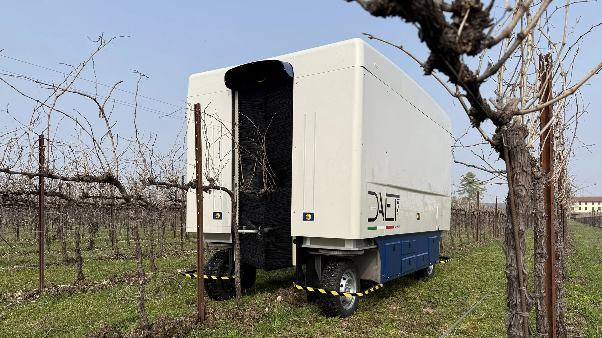 The autonomous winter vine pruning machine A.P.M.-01 among the vines, a cane in the foreground